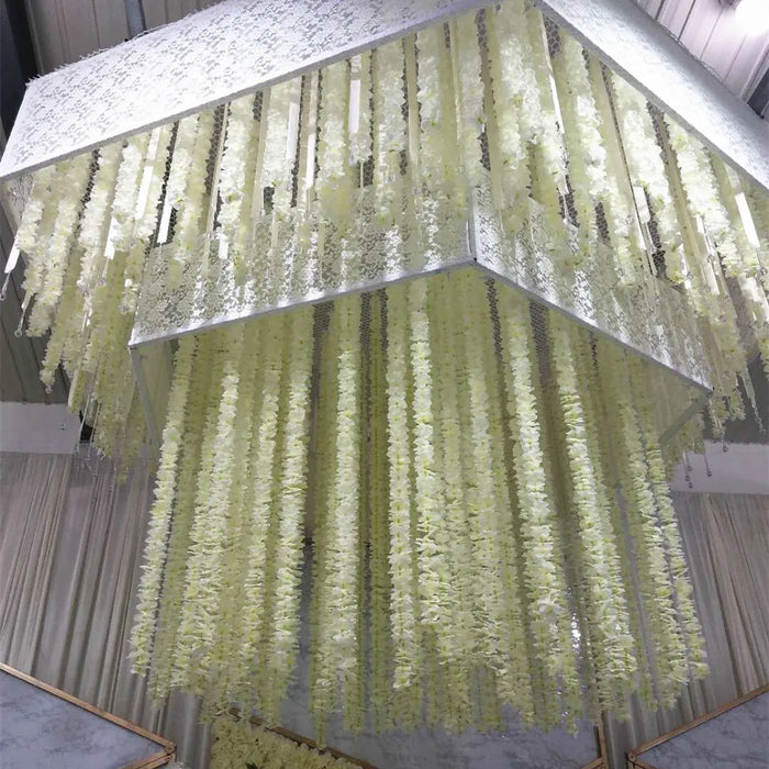 Guirlande de fleurs artificielles en soie et rotin orchidée suspendue sur un mur blanc