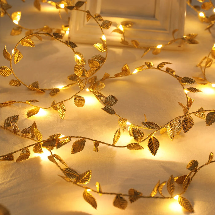 Guirlande lumineuse LED feuilles dorées sur un mur blanc