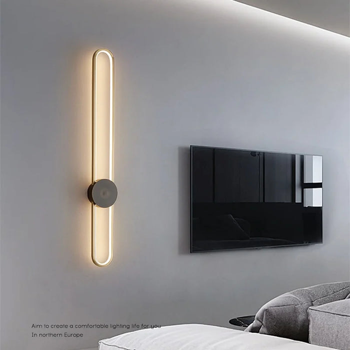 Applique murale LED moderne noire et or allumée dans un salon contemporain