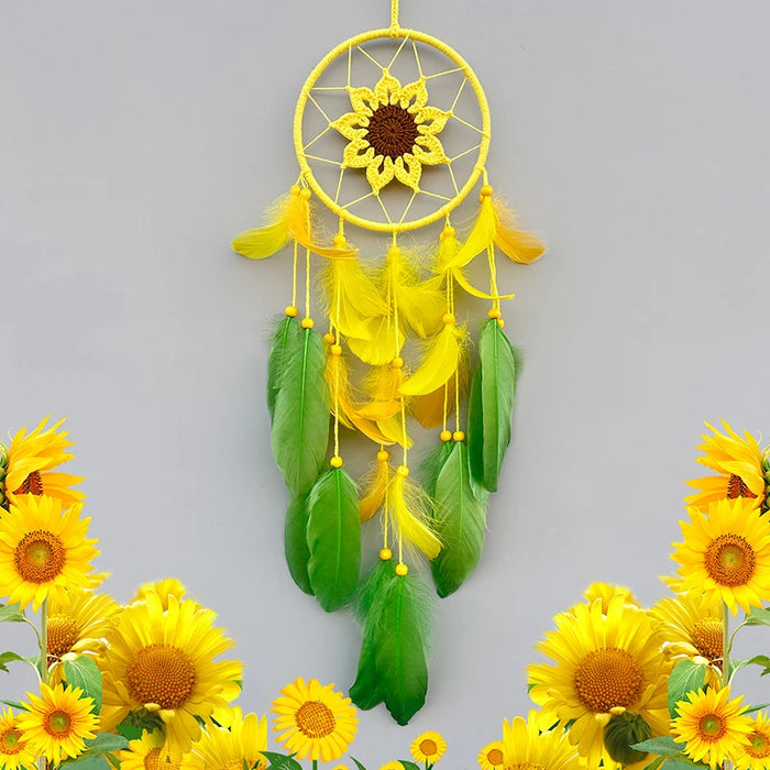 Un capteur de rêve décoratif avec un grand tournesol au centre, entouré de plumes jaunes et vertes, suspendu dans un cercle doré. Autour de l'objet, on voit de magnifiques tournesols jaunes.