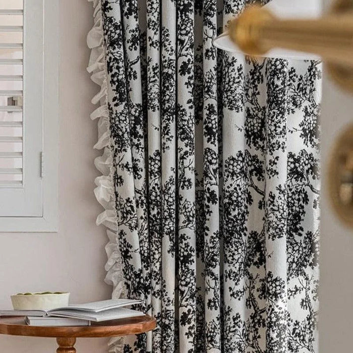 Rideau à motifs noirs sur fond blanc décorant un salon contemporain. Idéal pour ajouter une touche élégante et intemporelle à votre intérieur, ce rideau offre une belle intégration avec une décoration moderne. Parfait pour filtrer la lumière tout en créant une ambiance chaleureuse et accueillante.