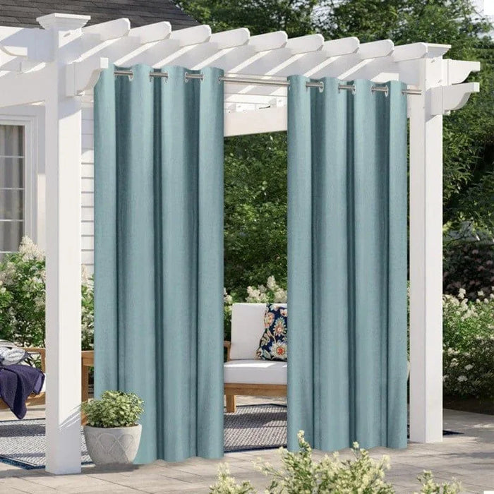 Rideaux d'extérieur bleus suspendus à une pergola blanche dans un jardin, offrant une ambiance élégante et intime pour les espaces extérieurs.