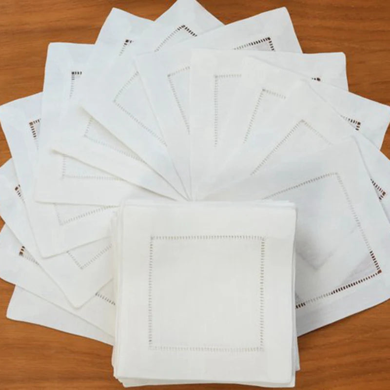 Une pile de serviettes blanches avec des bordures en pointillés sur une table en bois.