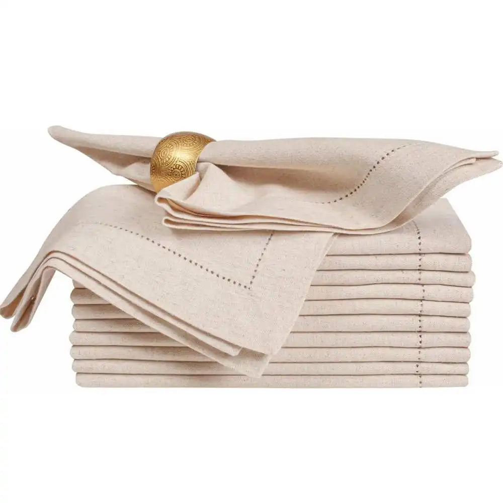 Une pile de serviettes de table élégantes en beige, ornées d'un anneau doré orné d'un motif traditionnel.