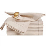 Une pile de serviettes de table élégantes en beige, ornées d'un anneau doré orné d'un motif traditionnel.