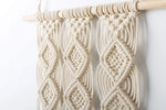 Macramé mural beige au-dessus d'un lit