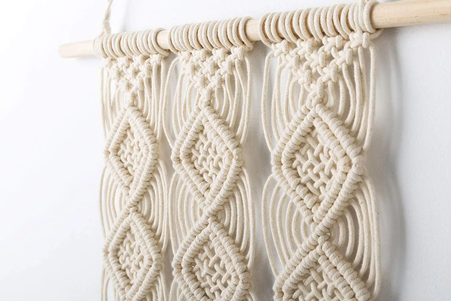 Macramé mural beige au-dessus d'un lit