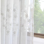 Voilage blanc brodé avec motifs floraux délicats en gros plan