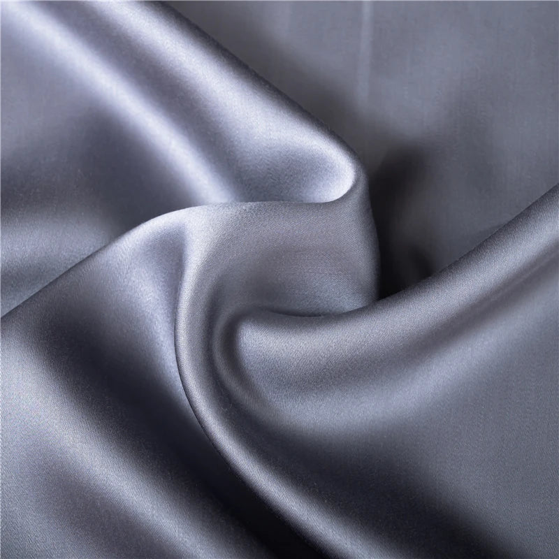 Housse de couette soie gris clair pliée sur lit
