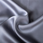 Housse de couette soie gris clair pliée sur lit