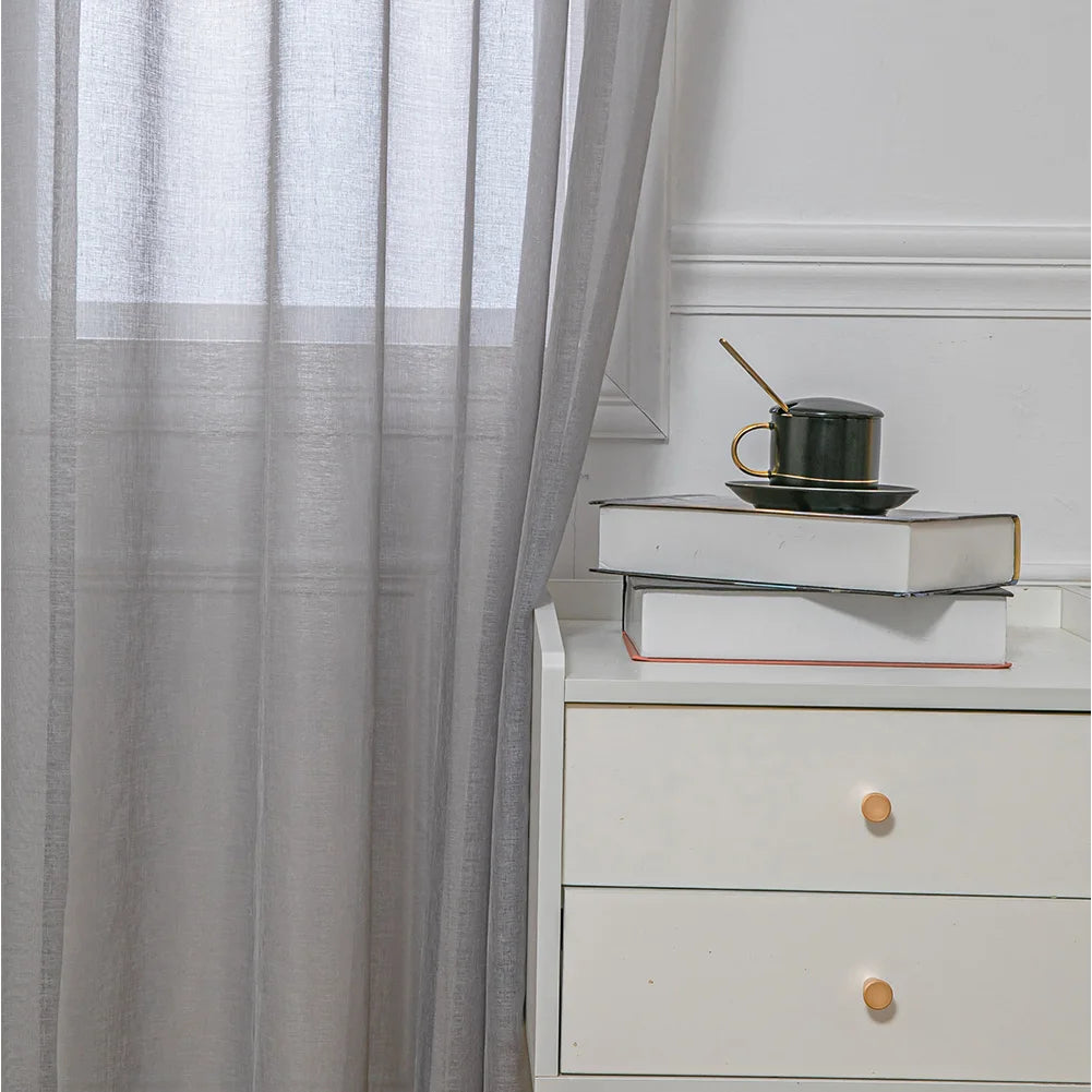 Image d'un rideau de fenêtre gris argenté, une option de couverture de fenêtre élégante et raffinée. Cet élégant traitement de fenêtre est fabriqué à partir d'un textile  de haute qualité et présente une finition en maille délicate pour un look sophistiqué. Parfait pour ajouter une touche de charme à n'importe quelle pièce, ce rideau est à la fois fonctionnel et esthétiquement plaisant.