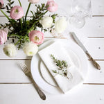 Une jolie table de fête avec de délicates fleurs roses et blanches, de la porcelaine et des couverts élégants, créant une ambiance raffinée et accueillante.
