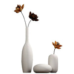 Trois vases blancs minimalistes contenant de belles fleurs d'automne à pétales orange et bruns.