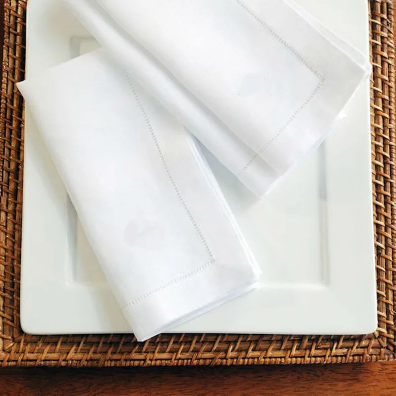 Gros plan sur un plateau en osier avec des serviettes de table blanches soigneusement pliées.