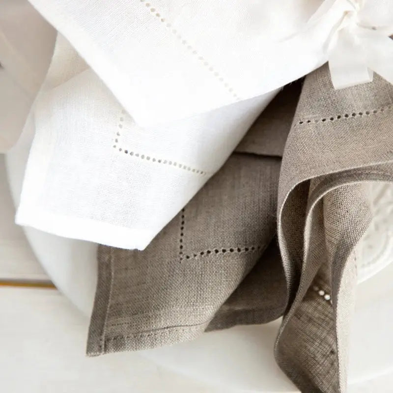 Serviettes de table blanches et grises, détail des coutures délicates.