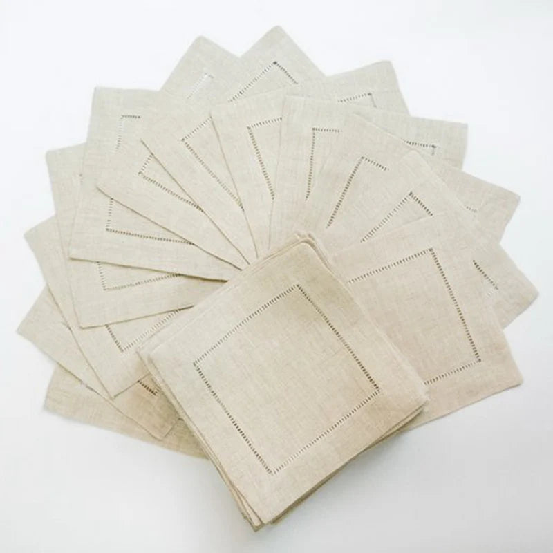 Un arrangement de serviettes en lin blanc sur fond blanc, avec des bordures gris foncé, suggérant une esthétique épurée et élégante.