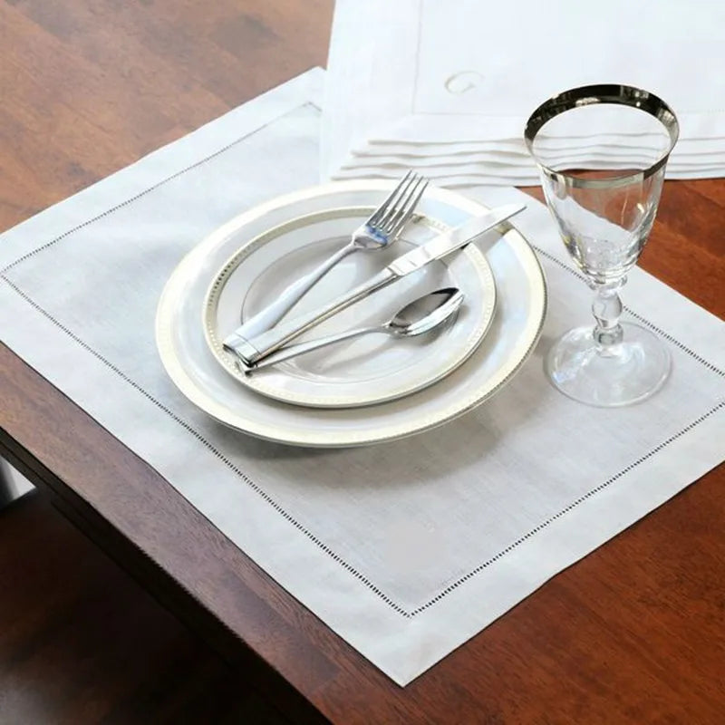 Une table élégante avec une assiette blanche, des couverts en argent et un verre de vin, prête pour un repas raffiné.