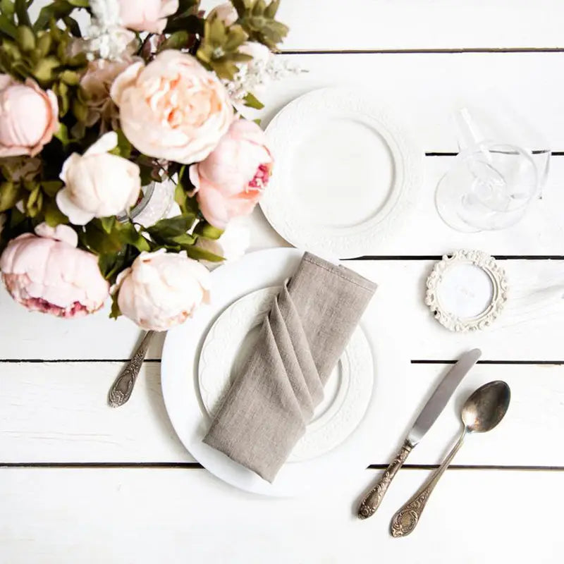 Une table blanche élégante, décorée de fleurs de pivoines roses et d'accessoires de table délicats, créant une atmosphère chic et féminine.