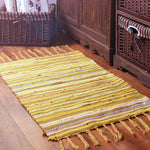 Tapis rayé jaune et blanc sur un sol en bois rustique avec des paniers en osier dans une atmosphère chaleureuse.