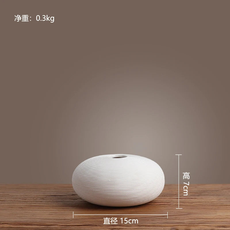 Un vase en céramique blanche aux lignes ondulées, posé sur une surface en bois foncé.