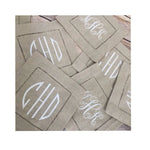 Pile de serviettes de table beige avec des motifs blancs qui semblent être des initiales ou un logo.