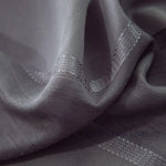 Gros plan sur la texture du tissu du voilage gris foncé, révélant les fibres tissées et les bandes légèrement brillantes.