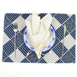 Cadre de table géométrique bleu marine et blanc avec assiette, couverts et tissu décoratif.
