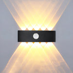 Applique murale extérieure LED noire avec détecteur de mouvement sur un mur de jardin