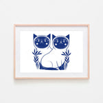 Deux chats bleus stylisés dans un cadre de bois sur un fond blanc.