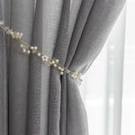 Rideau élégant en couleur grise avec embrasse décorative de perles et cristaux, parfait pour ajouter une touche raffinée à la décoration intérieure. Accessoire idéal pour personnaliser un salon ou une chambre, ce rideau apporte une ambiance chic et moderne. Adapté pour filtrer la lumière et créer une atmosphère apaisante.