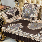 Coussins et couvre-lit ornés de motifs floraux élégants et de dentelle sur un canapé doré de style vintage.