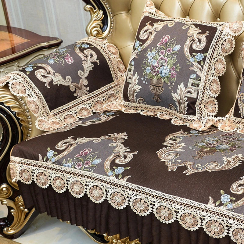 Coussins et couvre-lit ornés de motifs floraux élégants et de dentelle sur un canapé doré de style vintage.