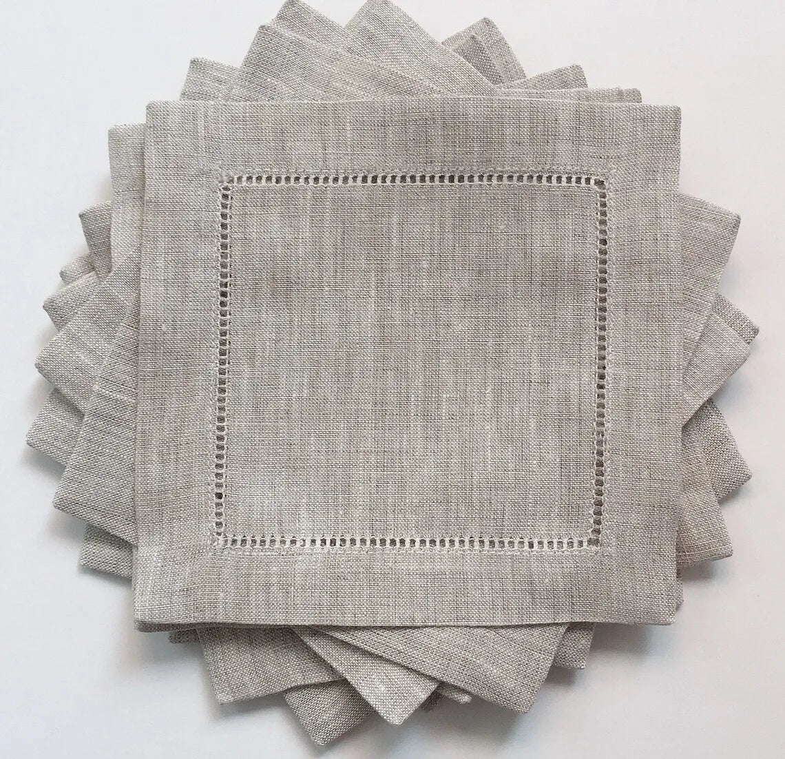 Serviettes de table gris clair en lin avec une bordure décorative ajourée.