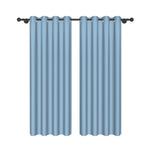 Deux rideaux bleu ciel à œillets, design moderne, suspendus sur une tringle noire, fond blanc uni.