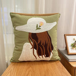 Coussin décoratif vert avec un motif appliqué d'une femme portant un chapeau de soleil.
