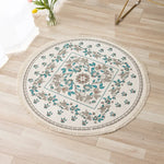 Tapis rond décoratif avec motifs floraux et feuillages en tons verts et beiges, posé sur un plancher en bois clair.