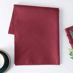 Un mouchoir en tissu de couleur bordeaux plié sur une surface blanche.