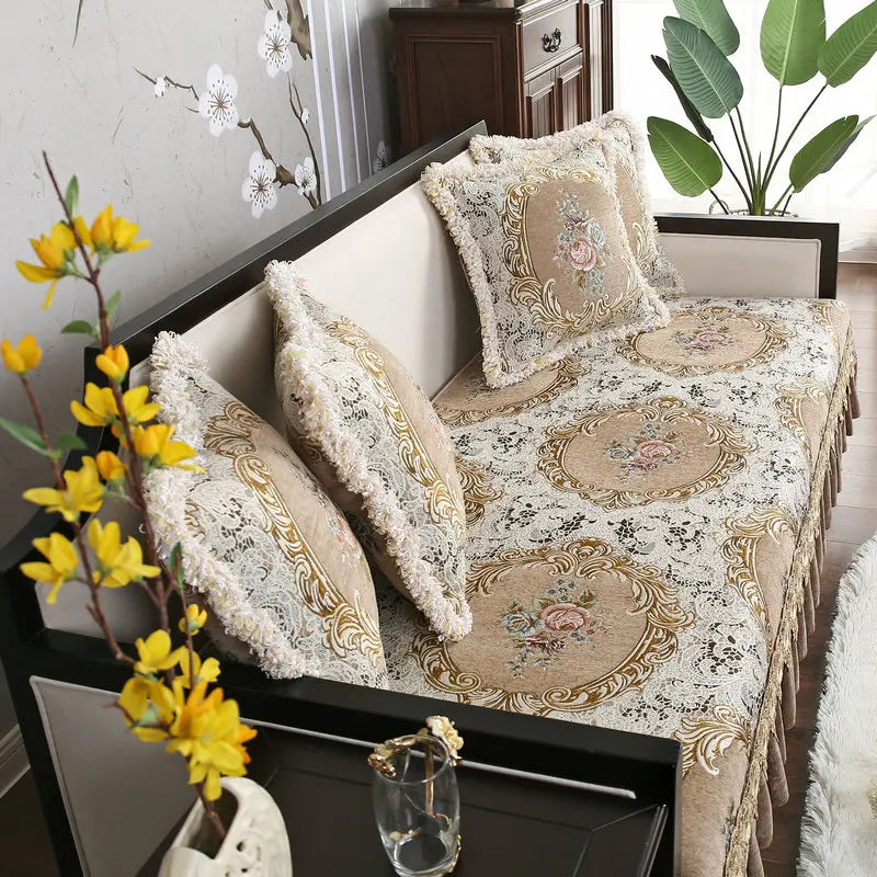 Un canapé confortable avec des coussins ornés de motifs floraux et de bordures dorées, placé dans un intérieur élégant et décoré avec des plantes.