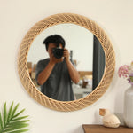 Miroir rond en rotin accroché au-dessus d'une console en bois
