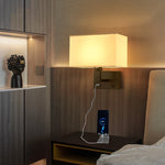 Applique murale LED installée près d'un lit avec abat-jour en tissu blanc