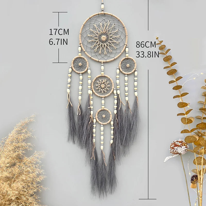 Rêve attrapeur décoratif suspendu aux motifs entrelacés et aux plumes grises.
