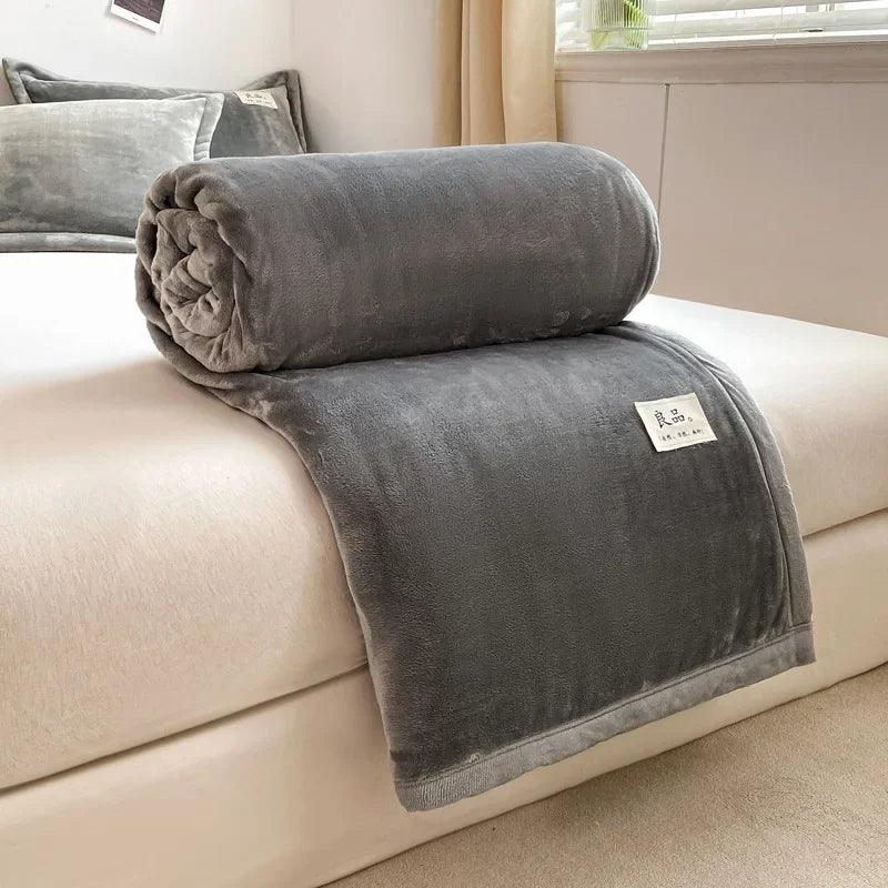 Une couverture gris foncé en velours douillet et confortable, parfaite pour se blottir et se réchauffer sur un canapé.