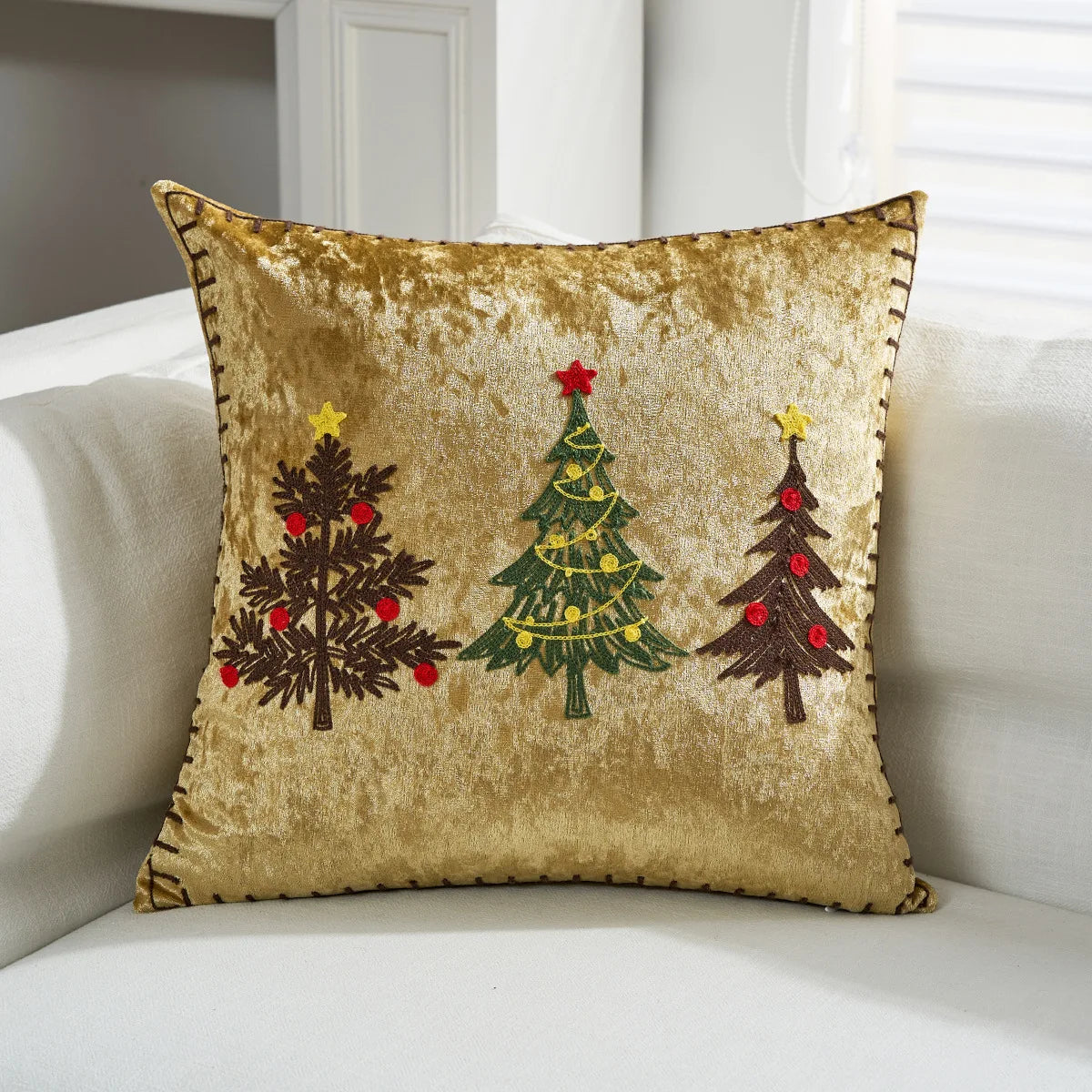 Coussin décoratif orné de motifs d'arbres de Noël sur un fond doré, représentant l'esprit des fêtes.