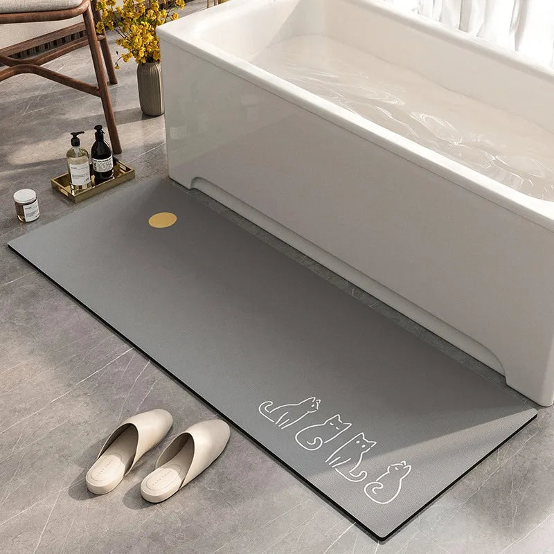 Un tapis de bain gris foncé avec un motif blanc de chat, installé près d'une baignoire blanche et d'accessoires décoratifs.