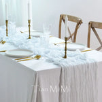 Une table de fête magnifiquement décorée, avec des chandelles dorées, des verres cristallins et une nappe blanche froissée, créant une ambiance élégante et raffinée.
