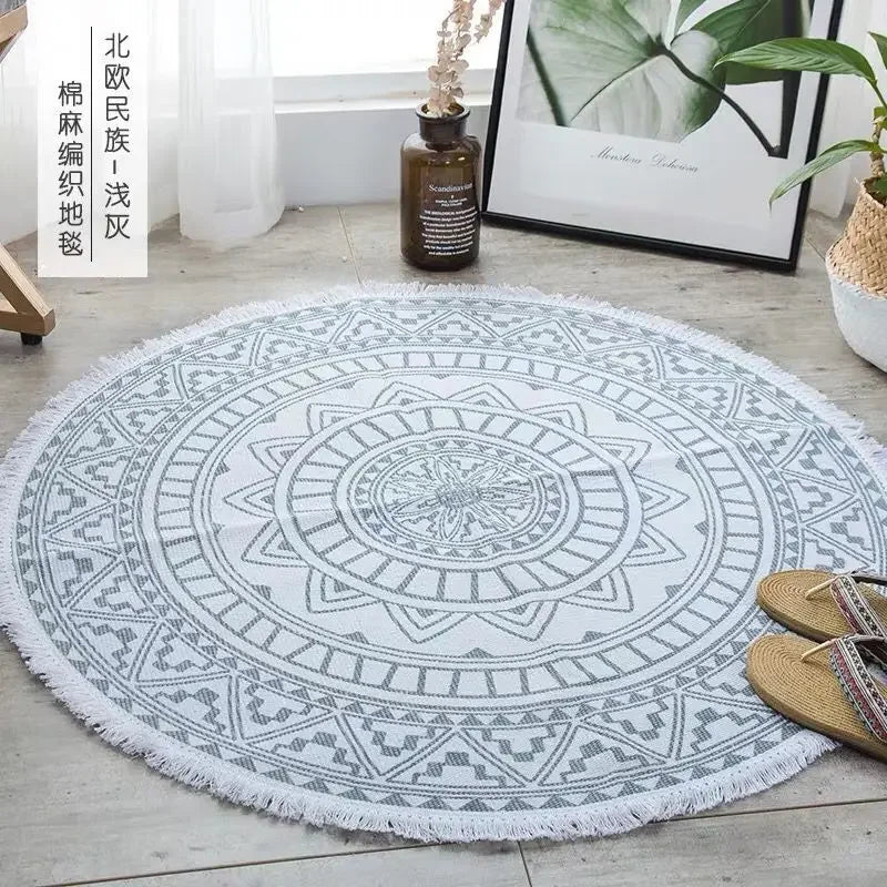 Tapis rond décoratif à motifs géométriques ethniques gris et blanc, posé au sol dans un intérieur moderne avec des plantes vertes.