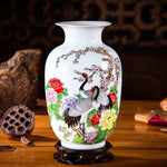 Vase décoratif en porcelaine blanche avec des motifs de grues asiatiques et de fleurs colorées.