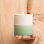 Bougie de cire blanche et verte pâle tenue dans les mains en gros plan.
