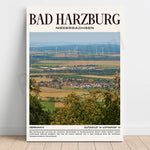 Un paysage de campagne vallonné avec des maisons colorées, des champs et des éoliennes dans la distance, offrant une vue panoramique sur la ville de Bad Harzburg en Allemagne.