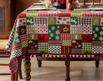 Nappe de table en patchwork colorée avec motifs de Noël, décorations florales et bougeoirs sur une table en bois.